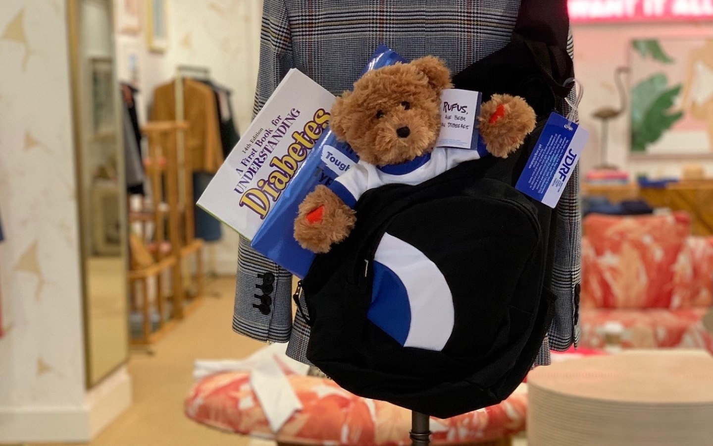 Photo of Rufus The Bear with Diabetes and other Bag of Hope items in a bookbag hanging in a Veronica Beard store.